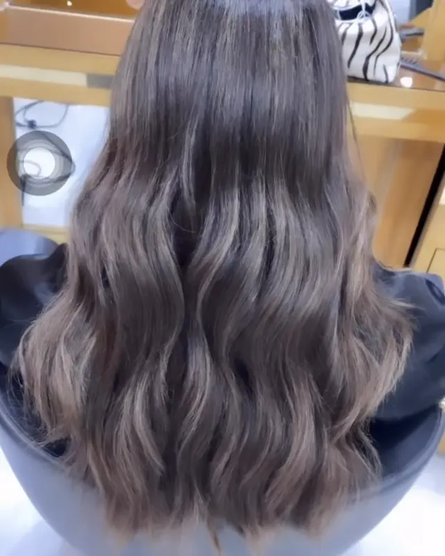 Balayage brun cendré sur cheveux ondulés